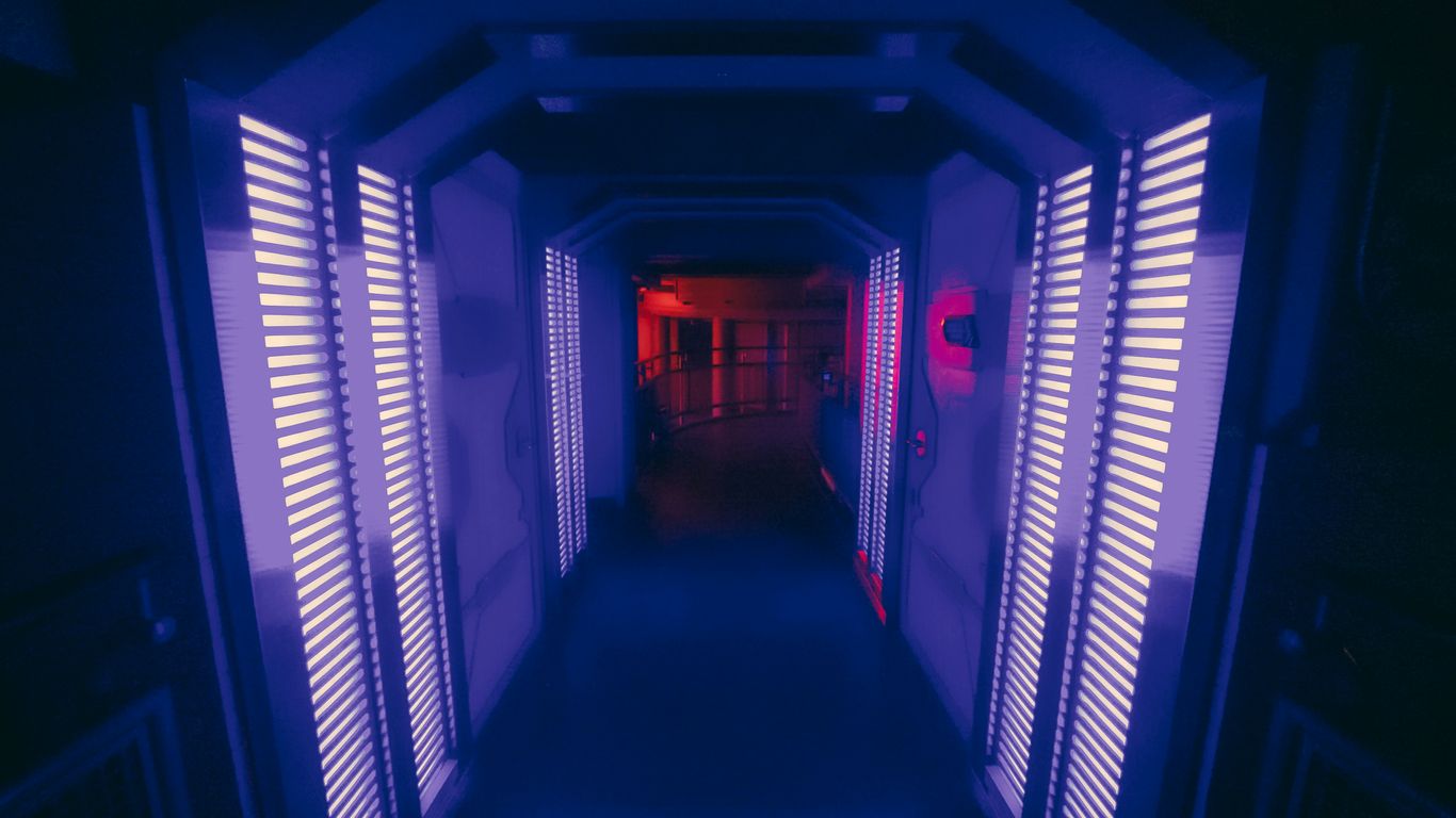 A long hallway with shutters leading to a red light