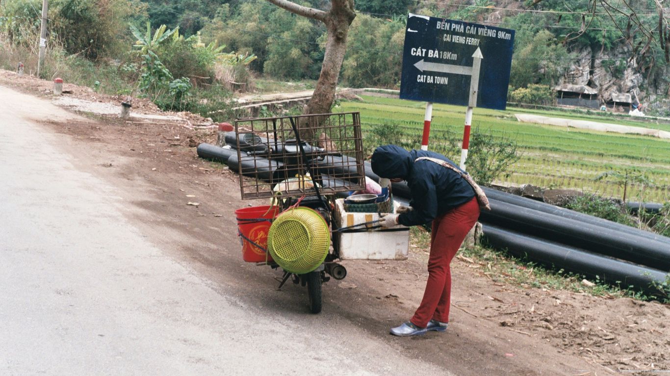 a person pushing a cart down a dirt road