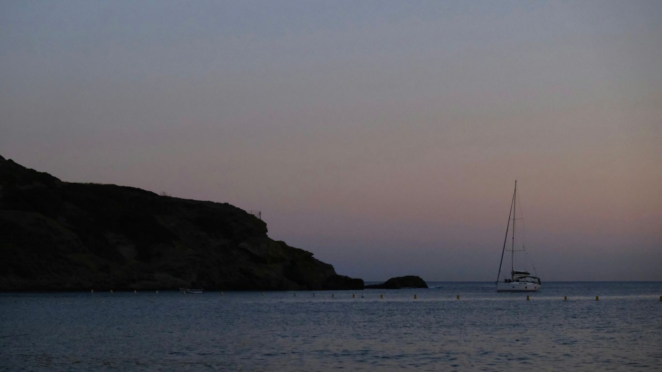 A sailboat is out on the water at sunset