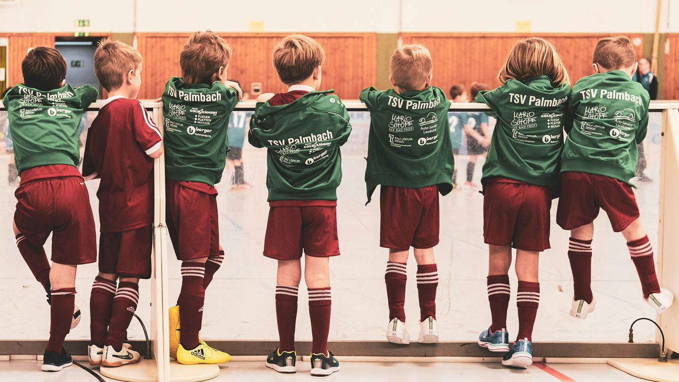 toddlers wearing sports jersey suit standing near white wall