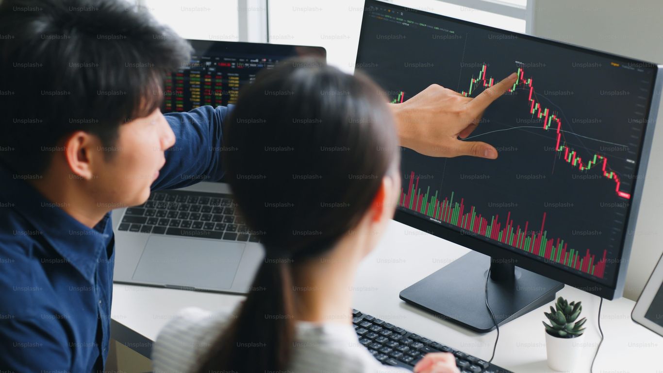 People analyzing financial data on computer screens together.