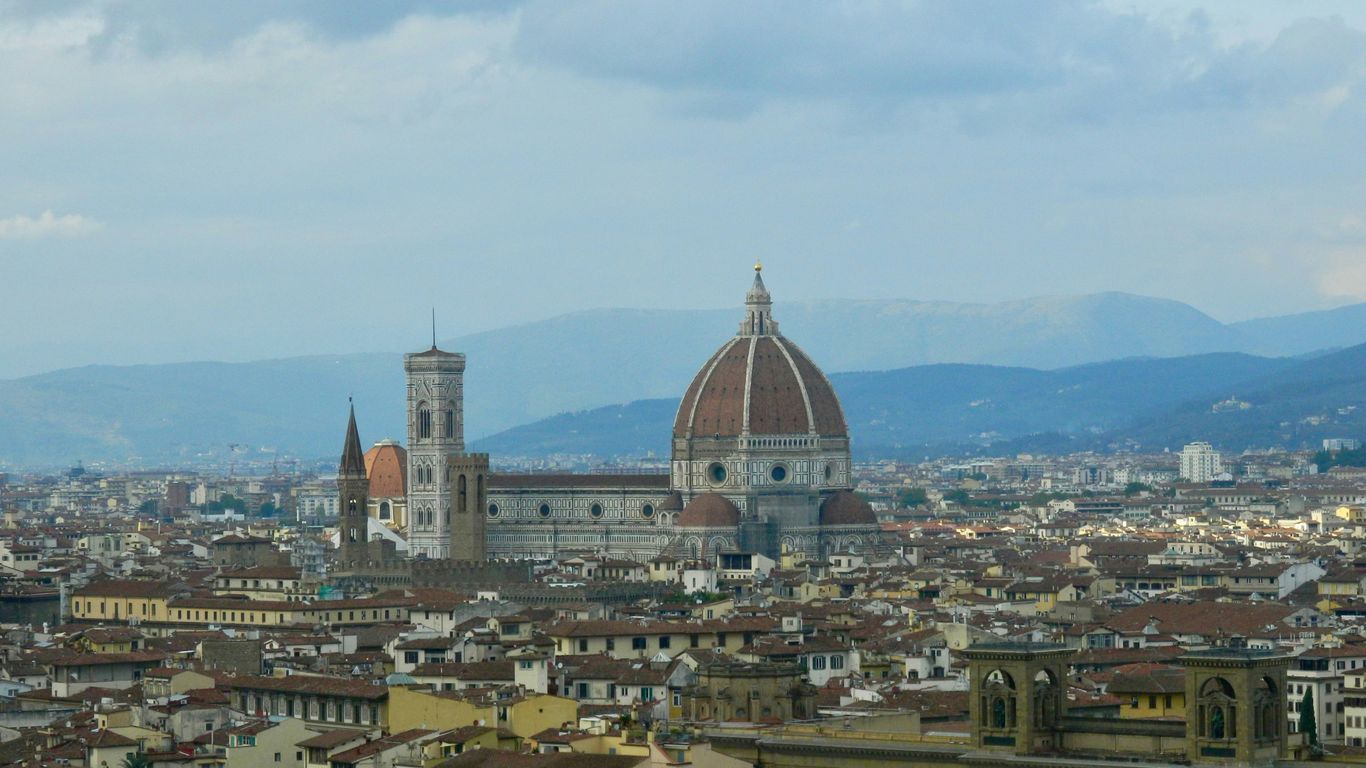 A view of a city with buildings and mountains in the background