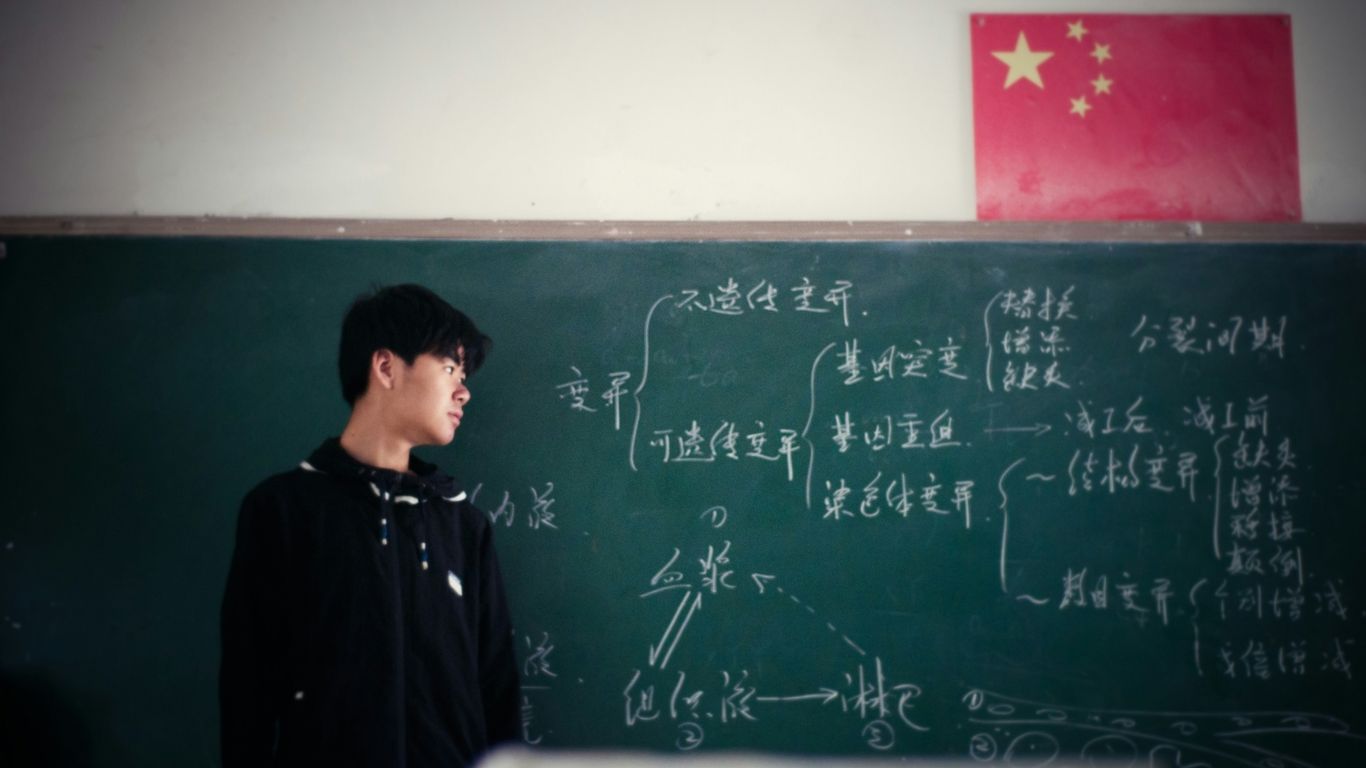 man standing in front of chalkboard inside classroom