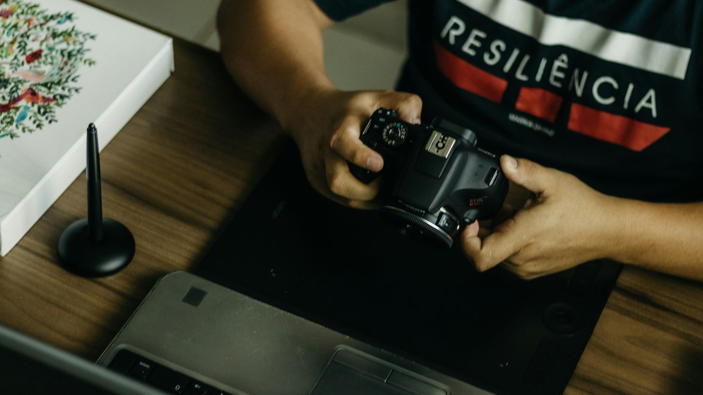 a man sitting at a desk holding a camera