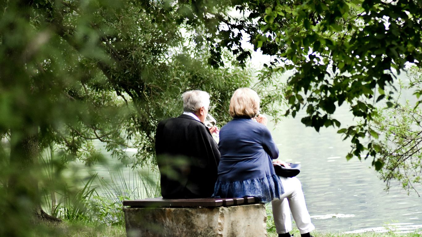 two people sitting on pavement facing on body of water