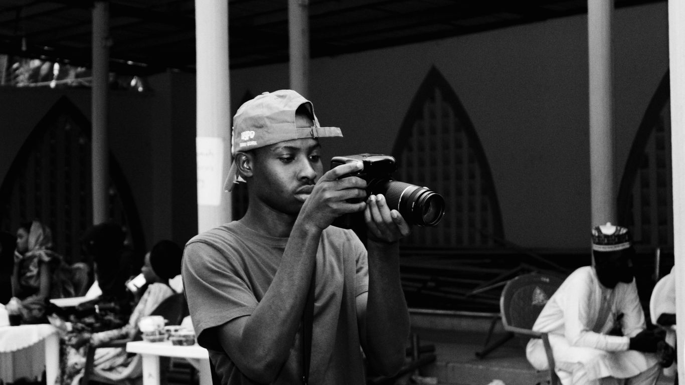 grayscale photography of man using DSLR camera