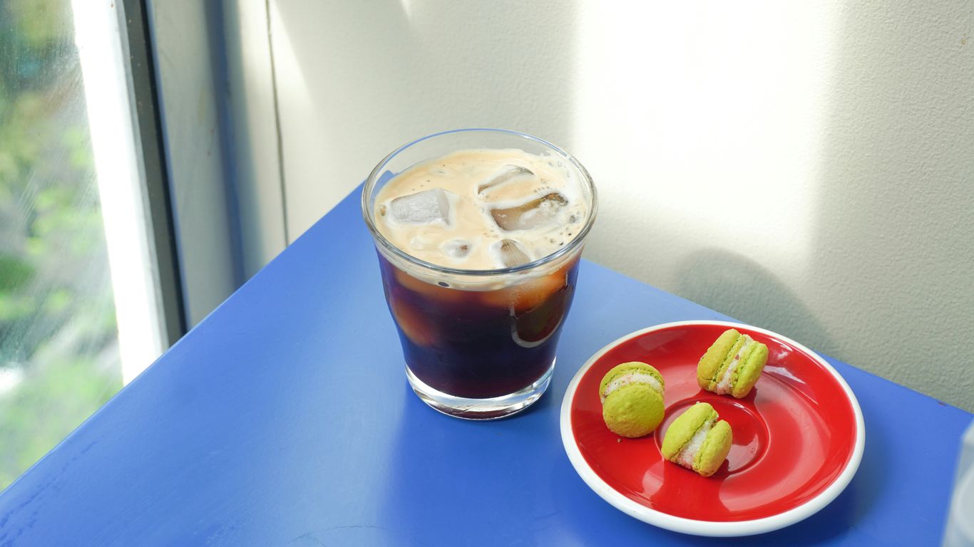 A red plate topped with apples next to a cup of coffee