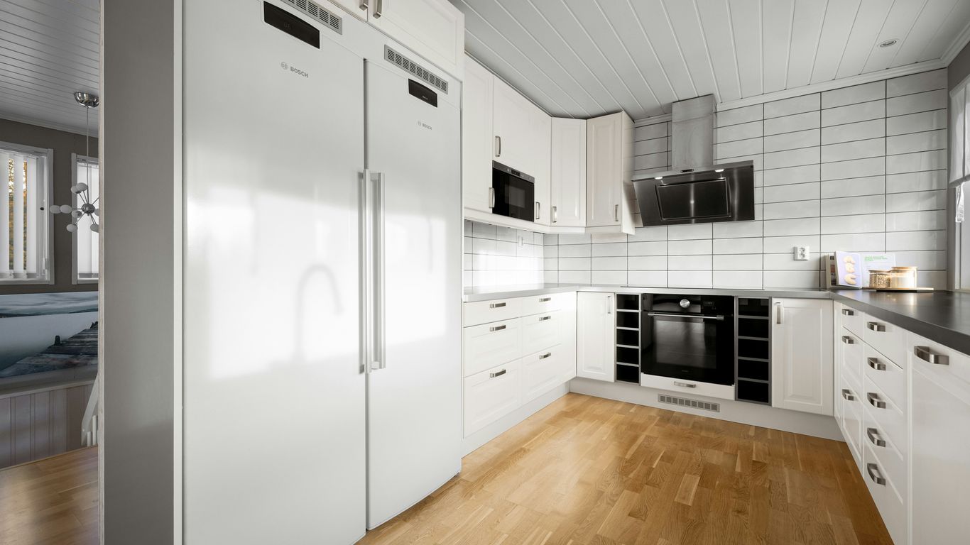 A kitchen with white cabinets and a wooden floor