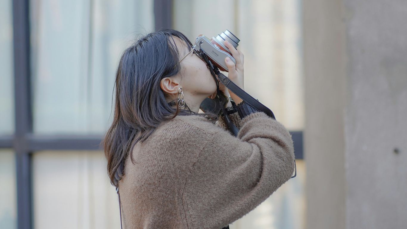 woman in brown sweater holding black smartphone
