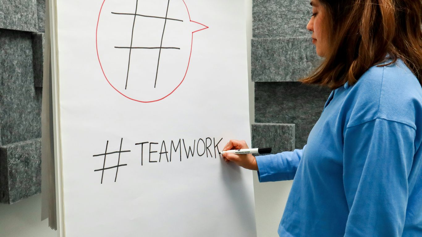 a woman writing on a white board with a marker
