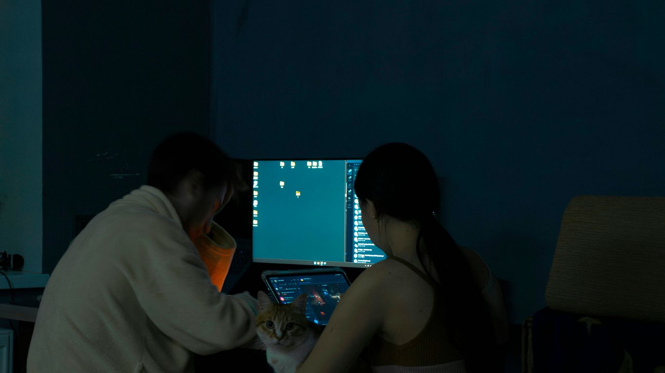 A man and a woman standing in front of a computer screen