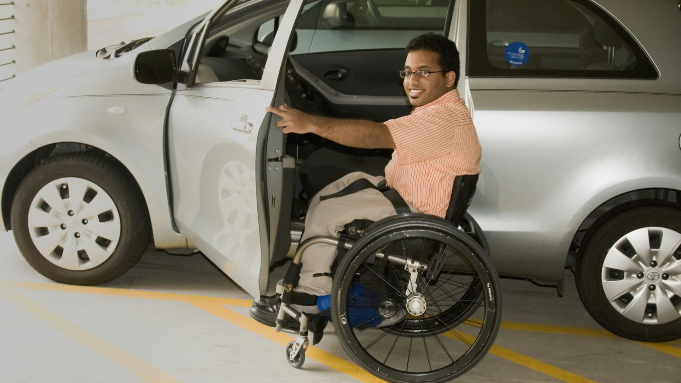 a man in a wheel chair next to a car