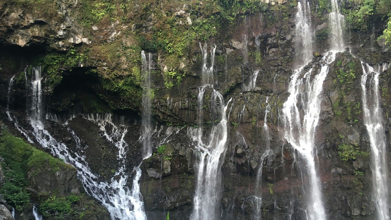 a group of people standing in front of a waterfall