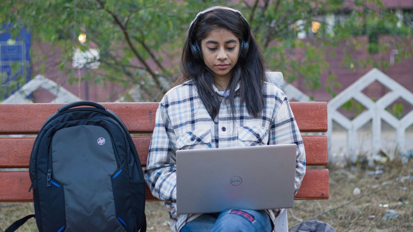 a girl sitting on a bench using a laptop