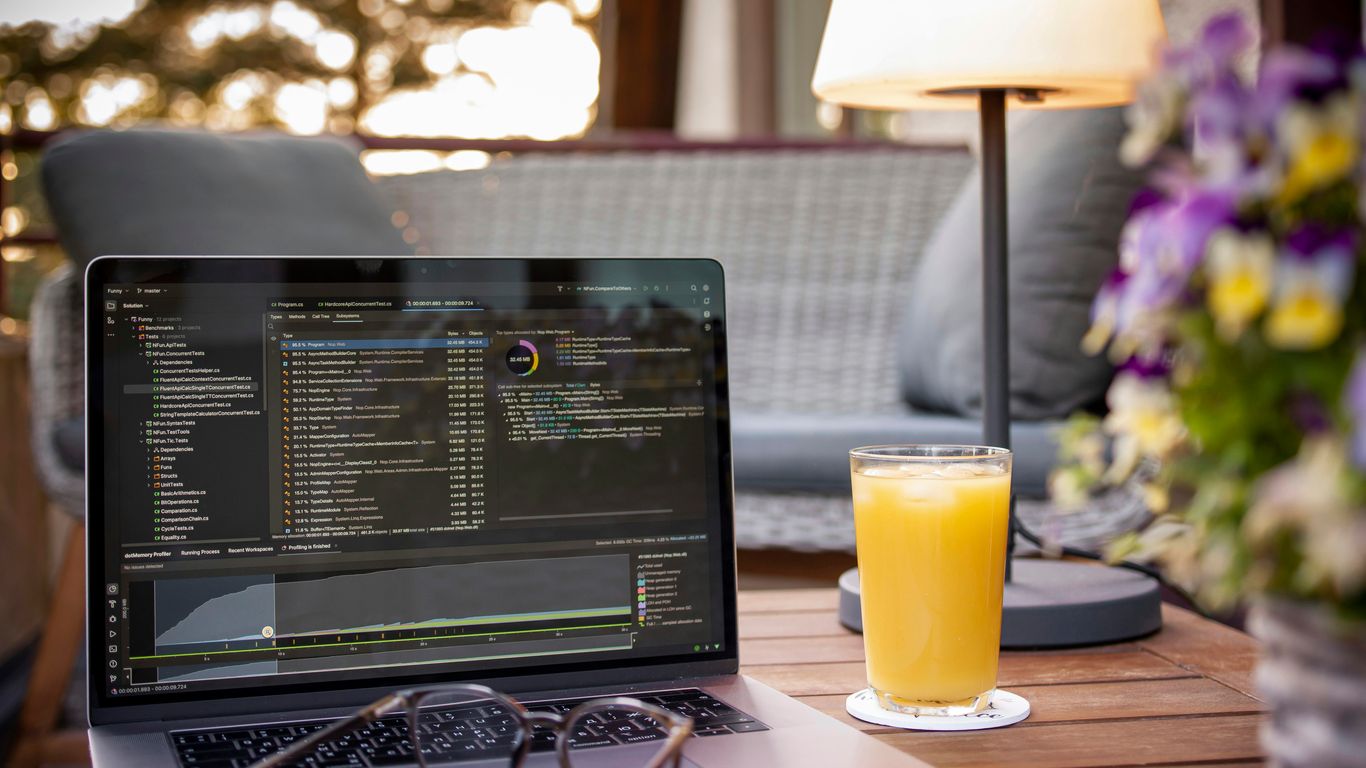 Laptop with code and orange juice on table