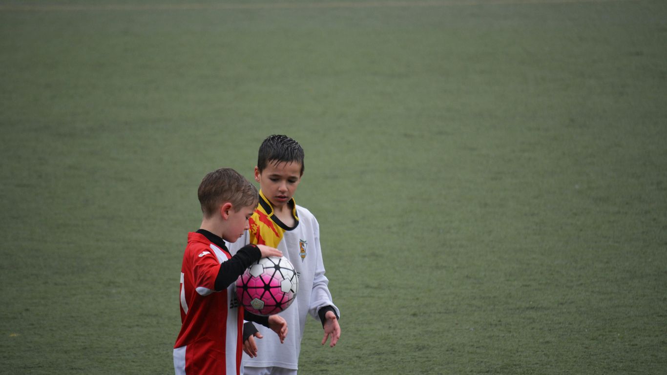 boy holding soccer ball beside other ball on soccer field