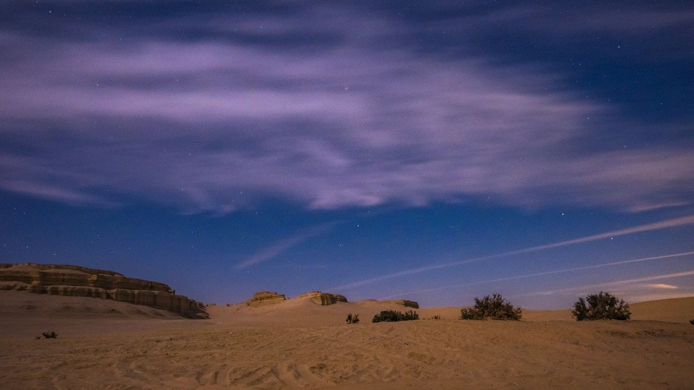 the night sky is lit up over the desert