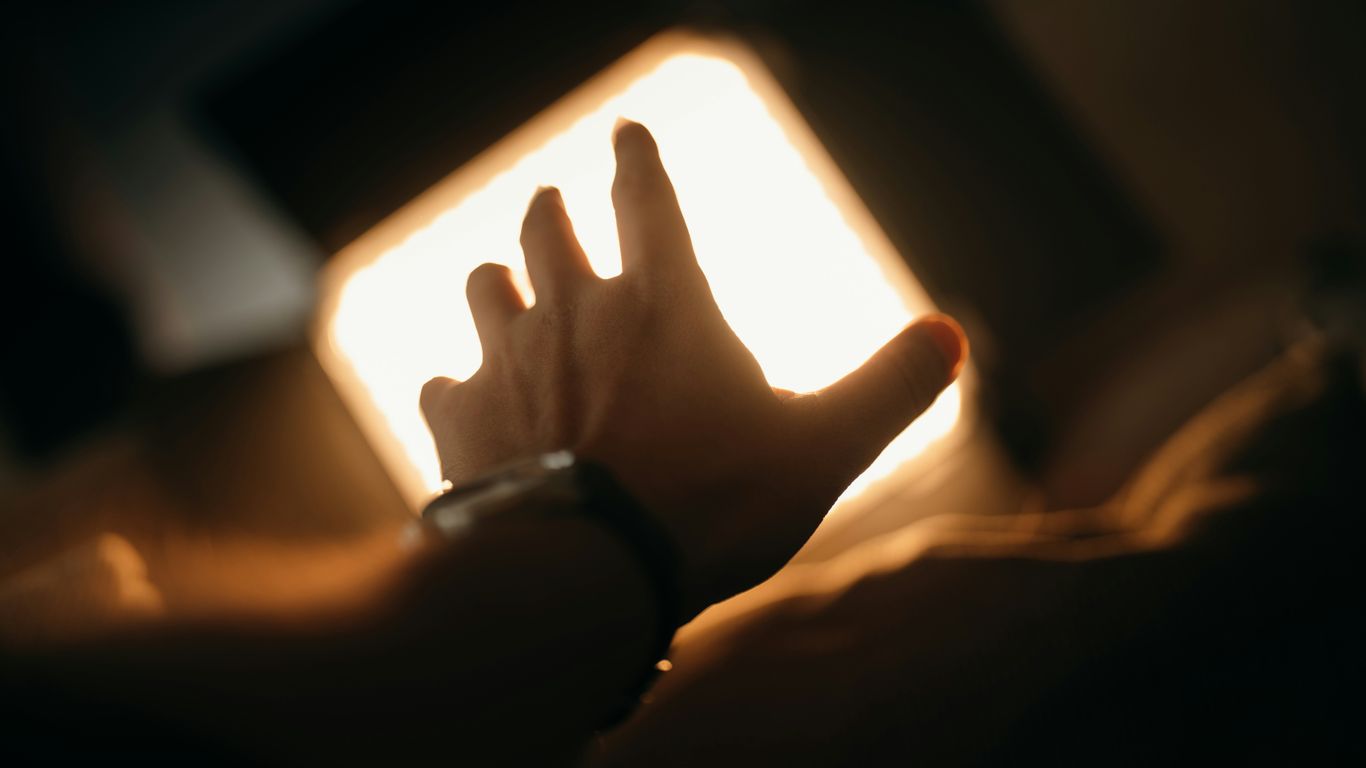 A person is reading a book in the dark