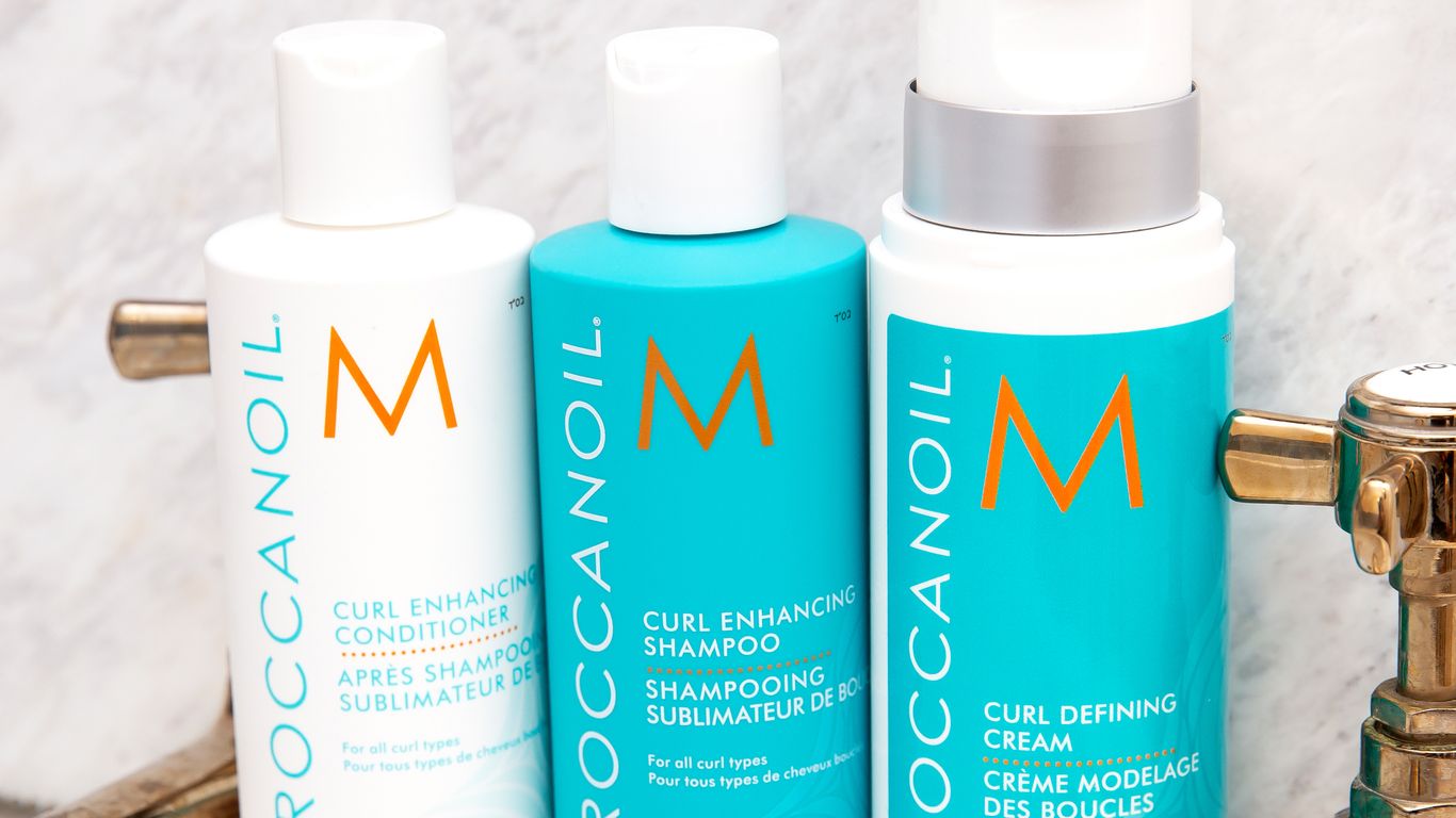 Three Moroccanoil hair care products on a marble background.