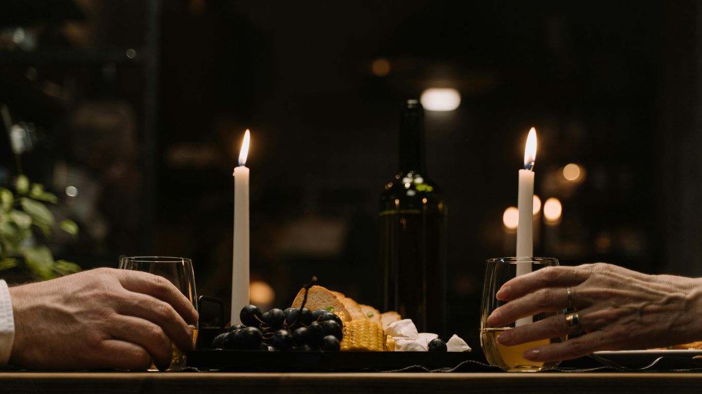 Candlelit dinner with wine, grapes, bread, and two people.