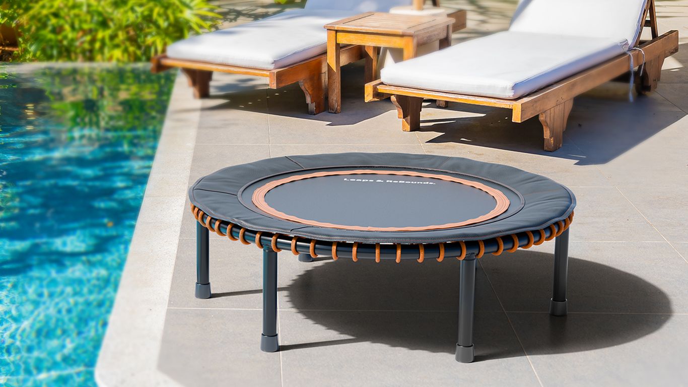 Mini trampoline by poolside with two lounge chairs nearby.