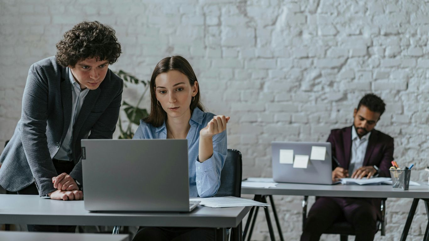 Two colleagues collaborating on a laptop in office.