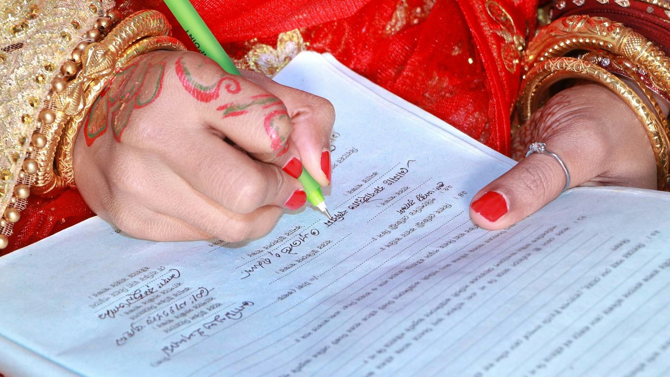 a woman in a red dress writing on a piece of paper