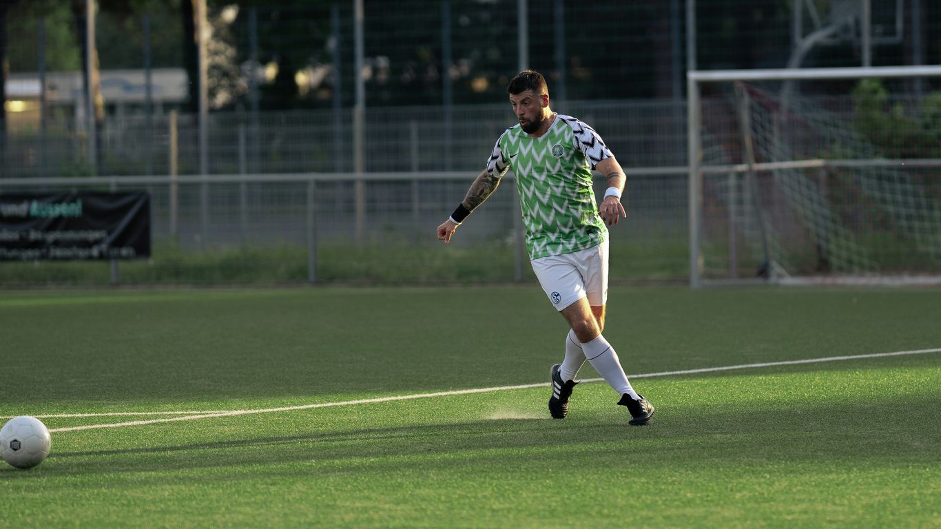 a man in a green and white uniform kicking a soccer ball