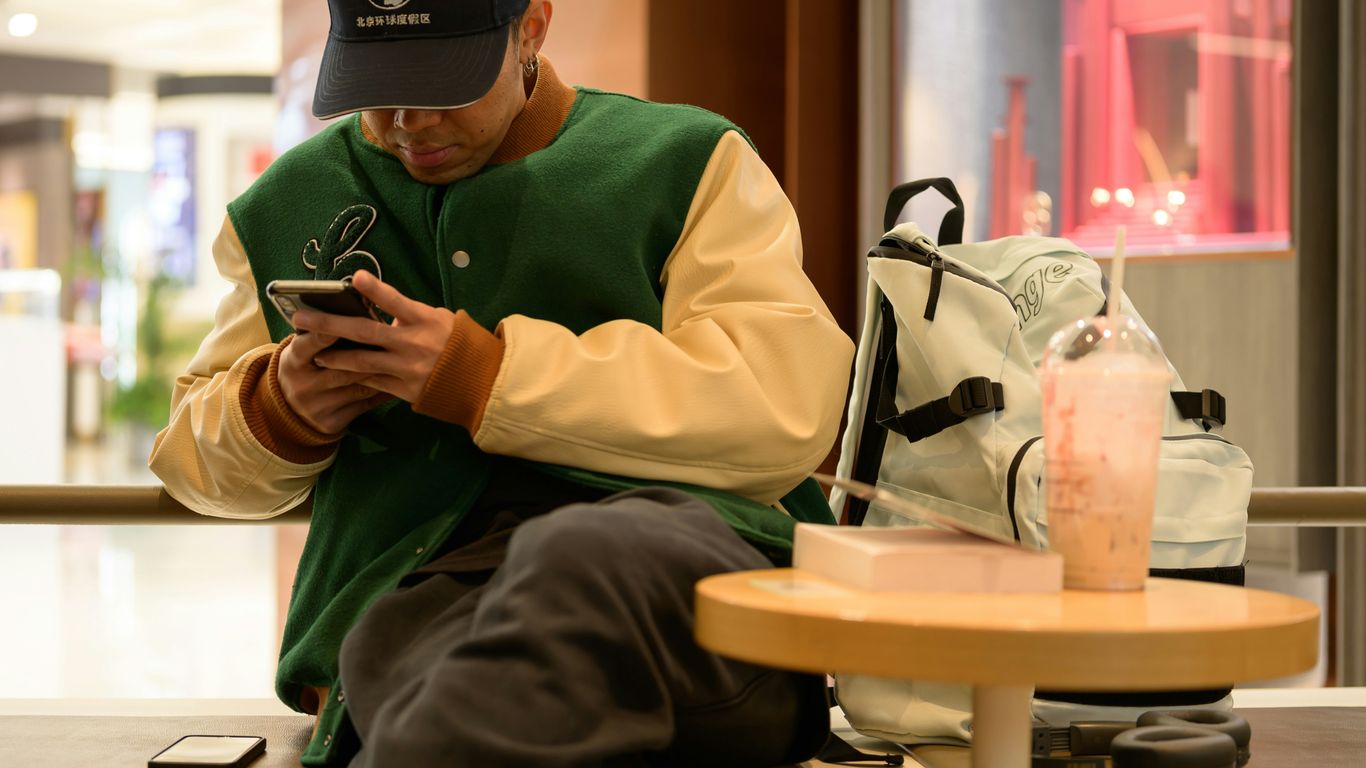 A man sitting on a bench looking at his cell phone