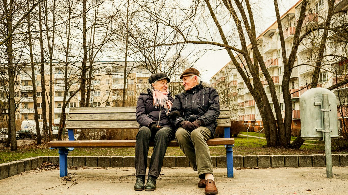 Elderly couple happily sitting on a bench together.
