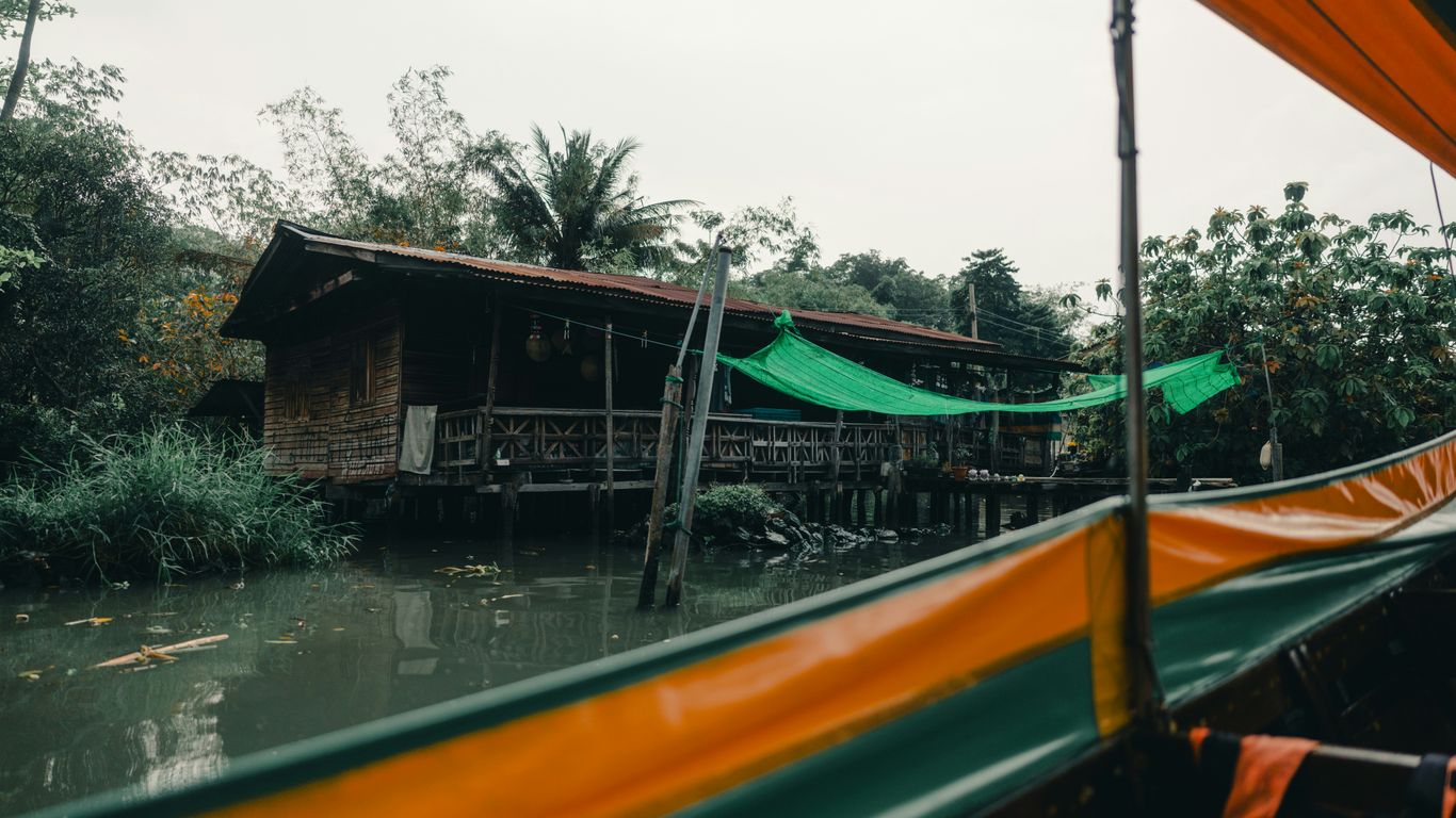 A boat ride passes a waterside house.