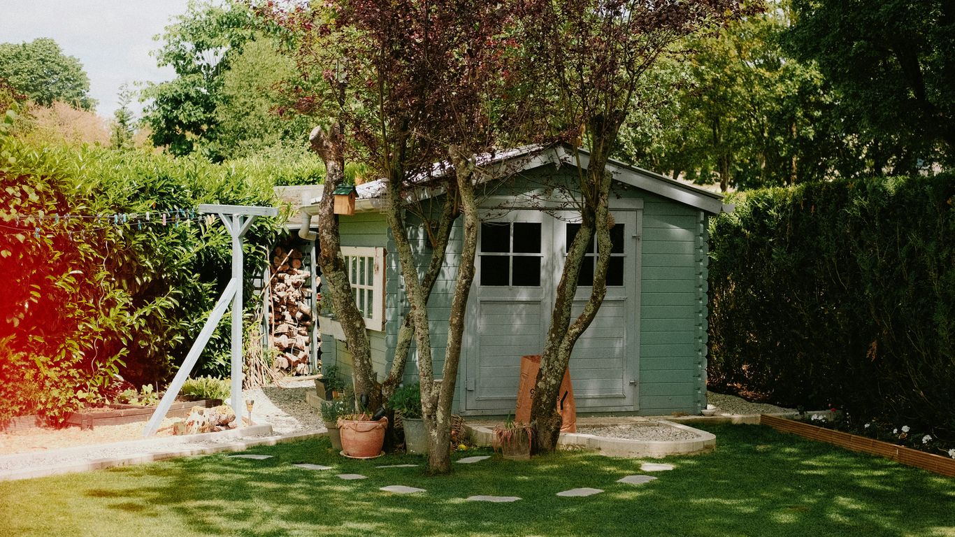 a small shed with a tree in the yard