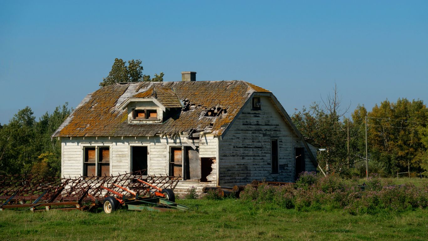 an old run down house in the middle of a field