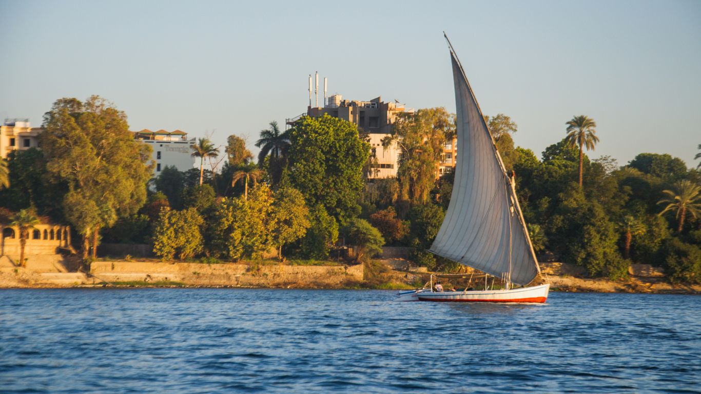a sailboat on the water with a city in the background
