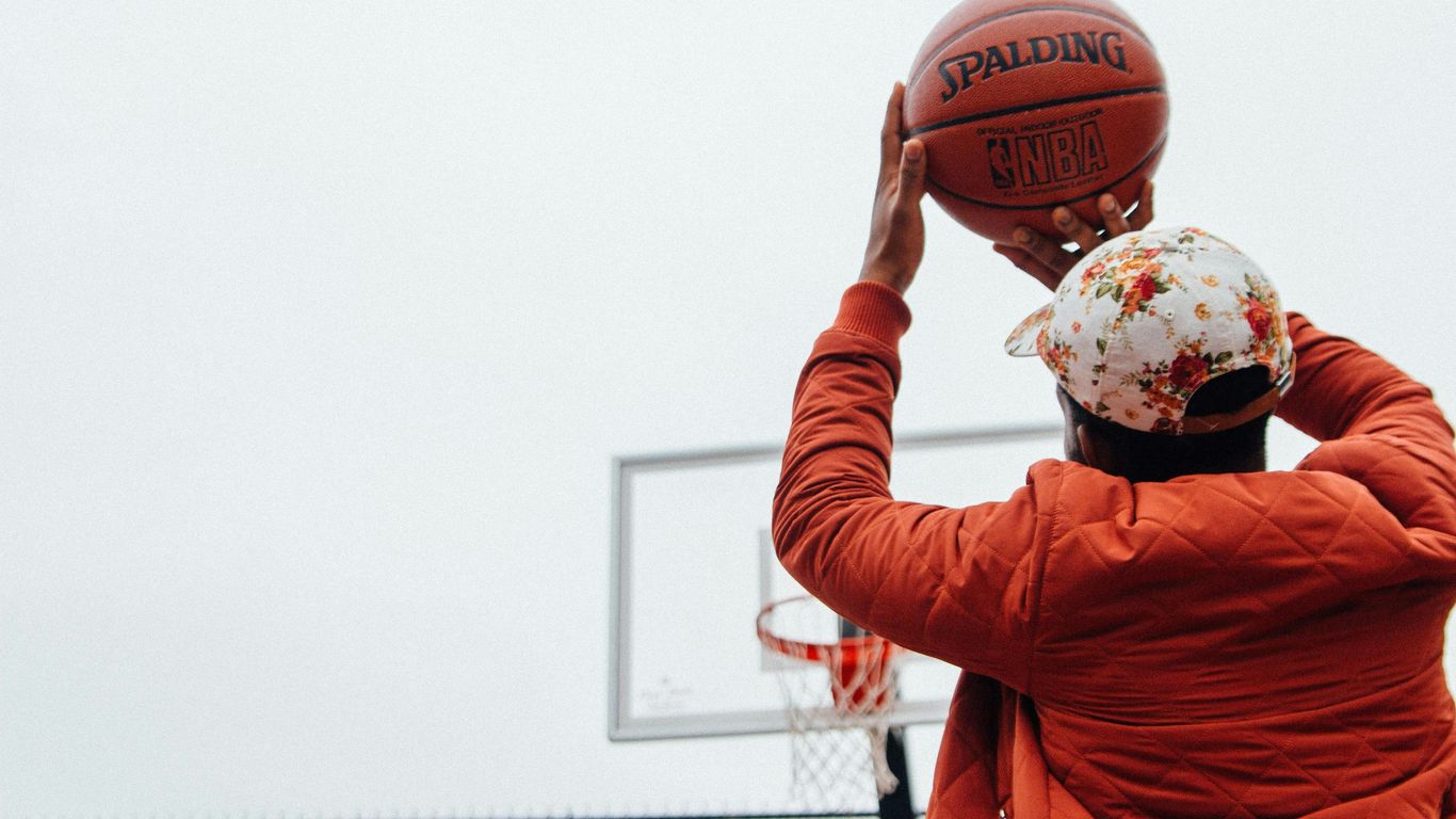 person holding basketball looking at basketball hoop system