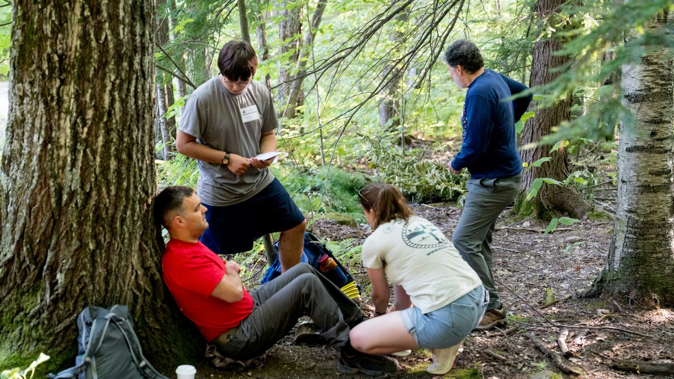 Four people gathered in a forest clearing