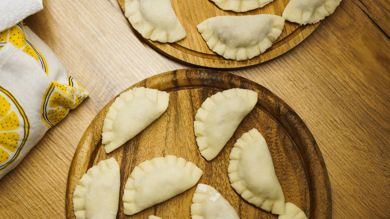Raw pierogi arranged on wooden boards