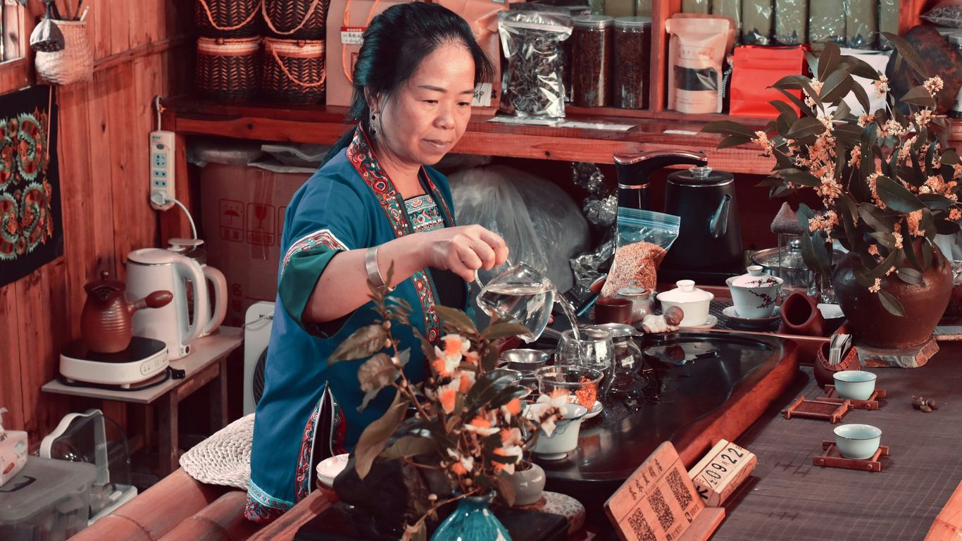 A woman is working on a vase in a shop