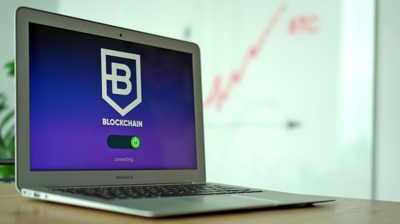 Laptop displaying a blockchain login screen with a progress indicator.