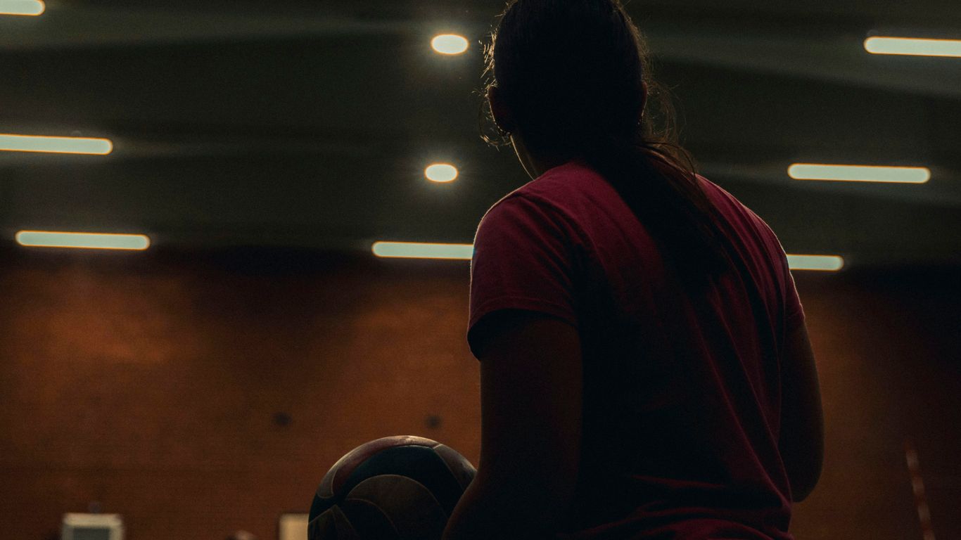 Young woman holding basketball in gymnasium.