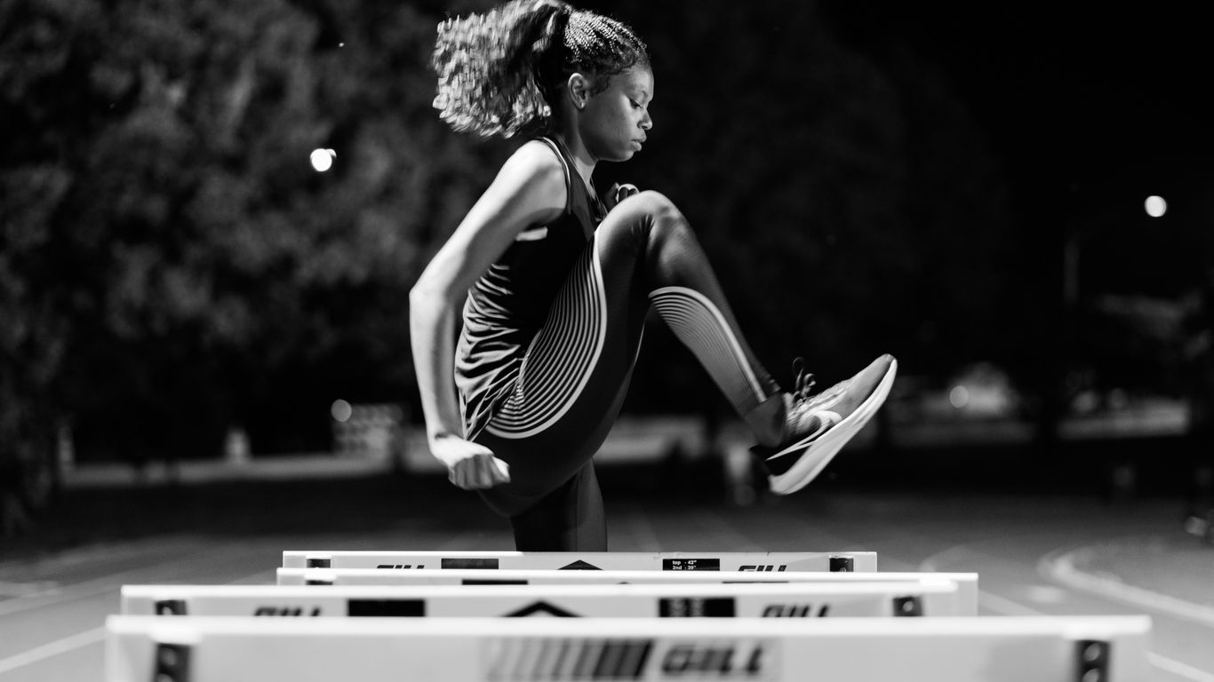 A woman jumping over a hurdle on a track