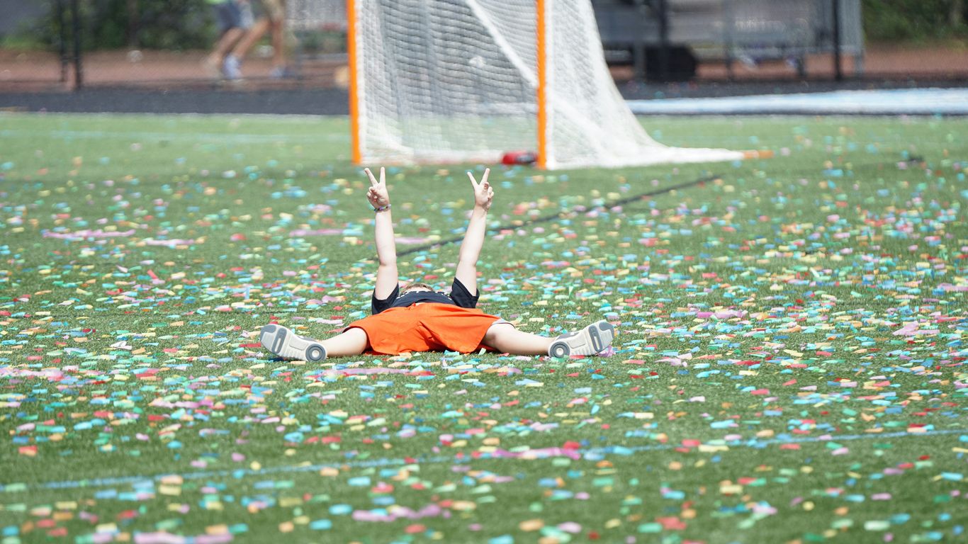 boy lying on soccer ground making hand peace sign