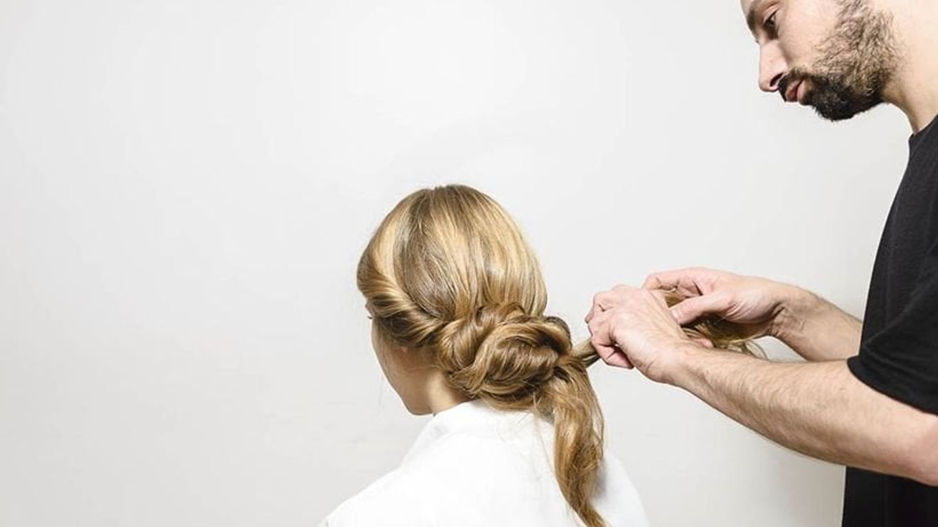 Person styling another's hair into an elegant bun.