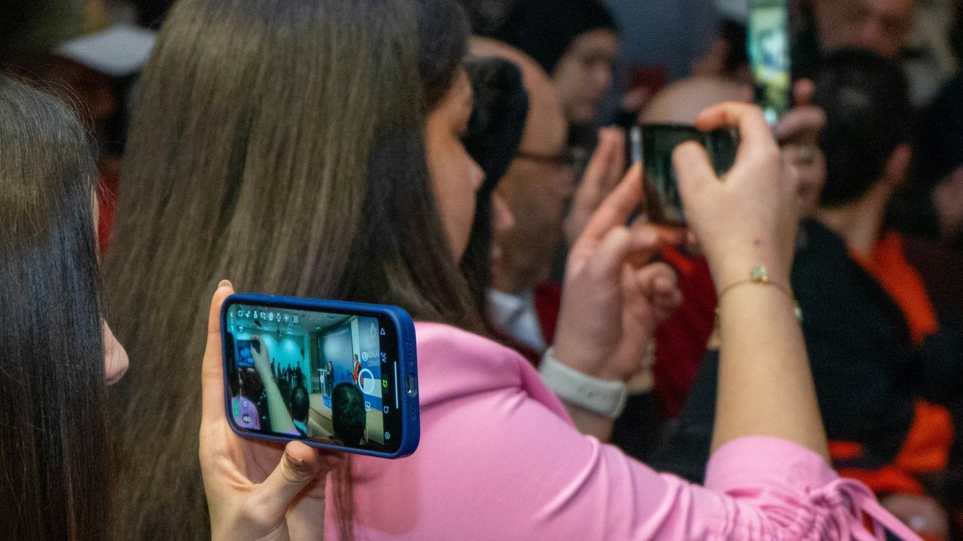 a group of people taking pictures with their cell phones