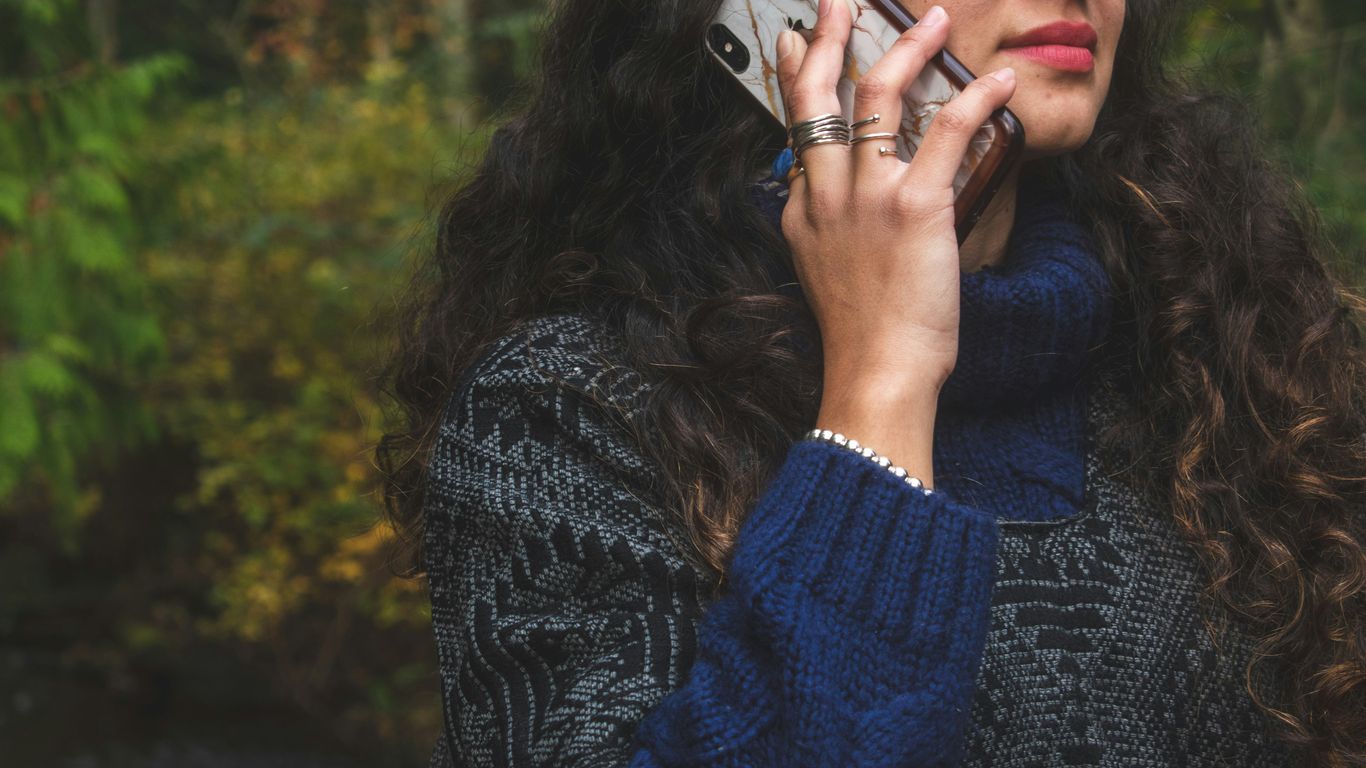woman in blue sweater holding smartphone