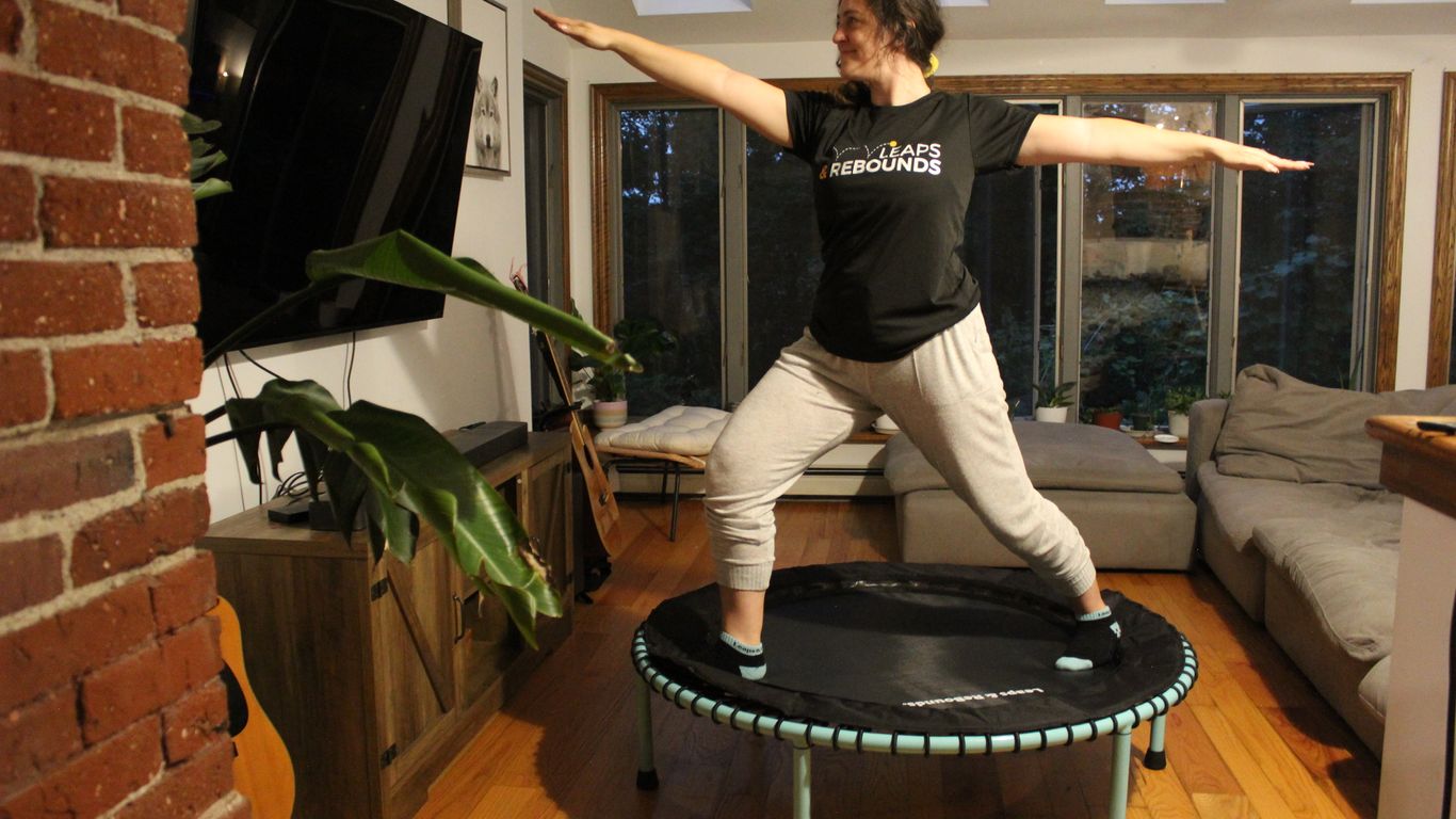 Person doing yoga pose on trampoline in cozy living room.