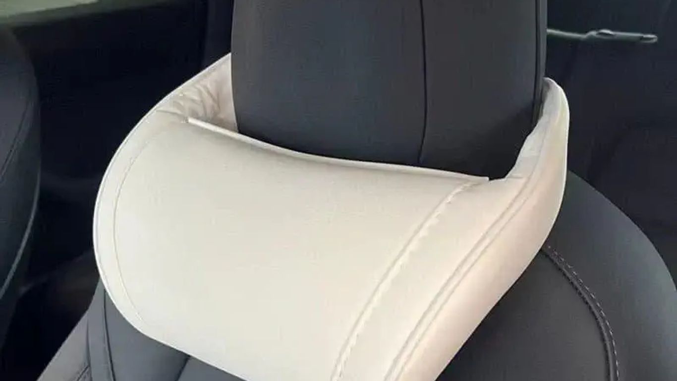 A white neck pillow attached to a car headrest.