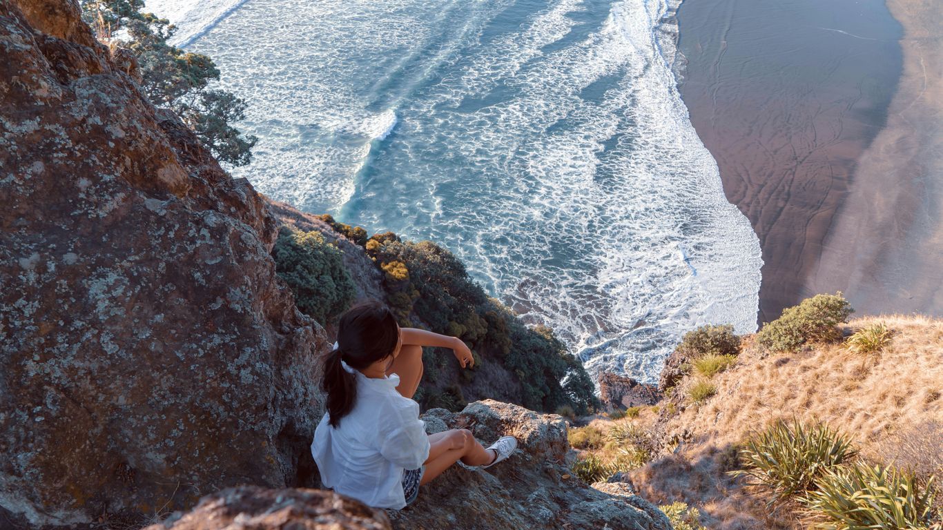 man in white t-shirt sitting on rock formation during daytime