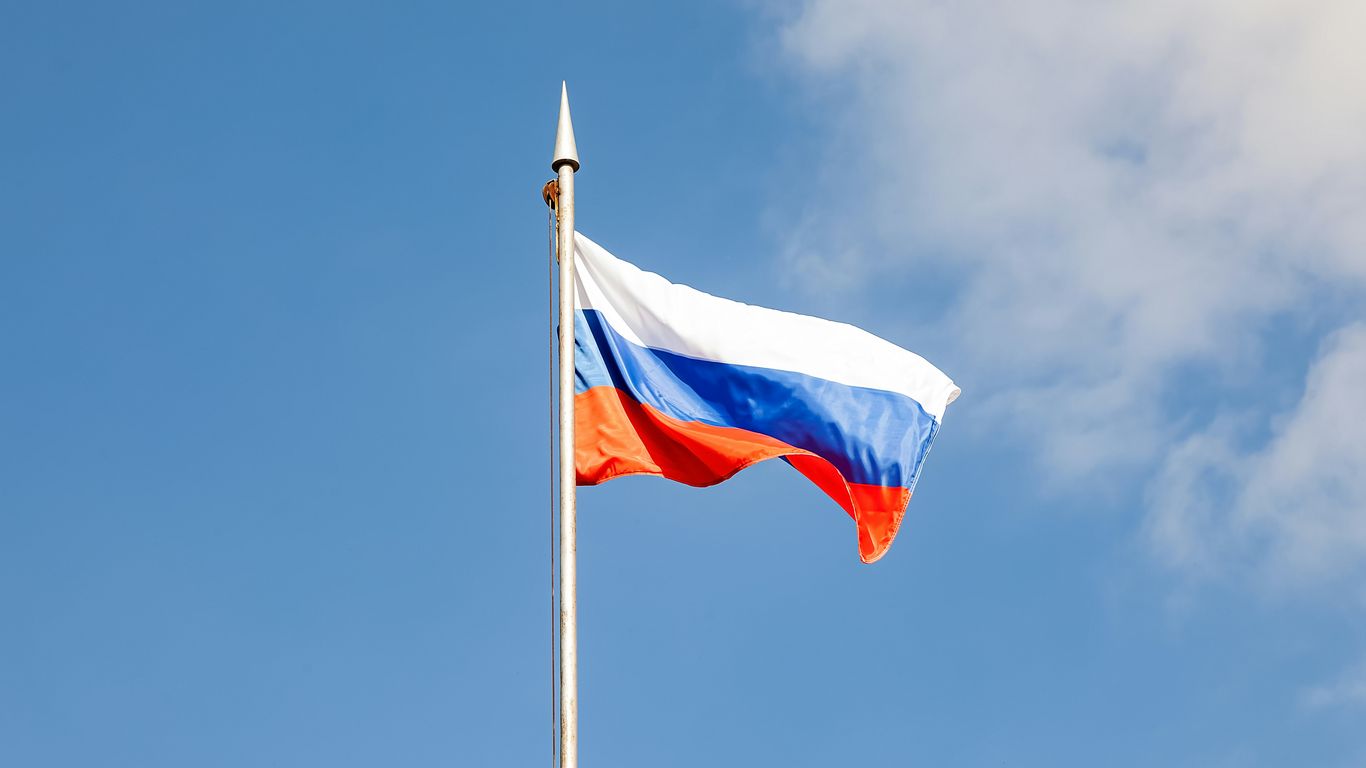 The russian flag waves against a clear, blue sky.