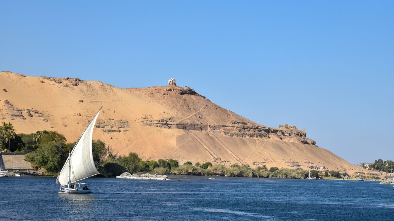 a sailboat in a body of water with a mountain in the background